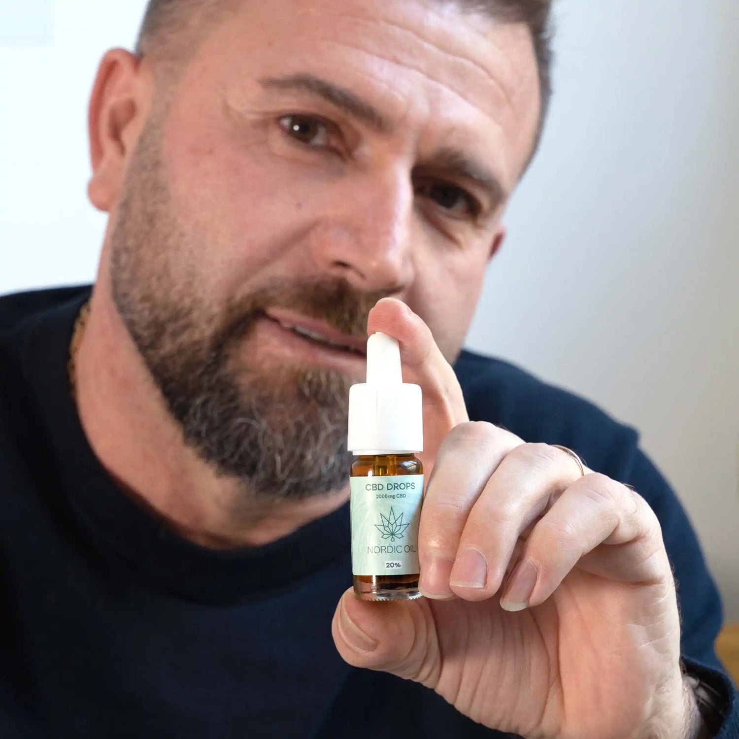 un uomo tiene in mano l'olio di CBD nella telecamera