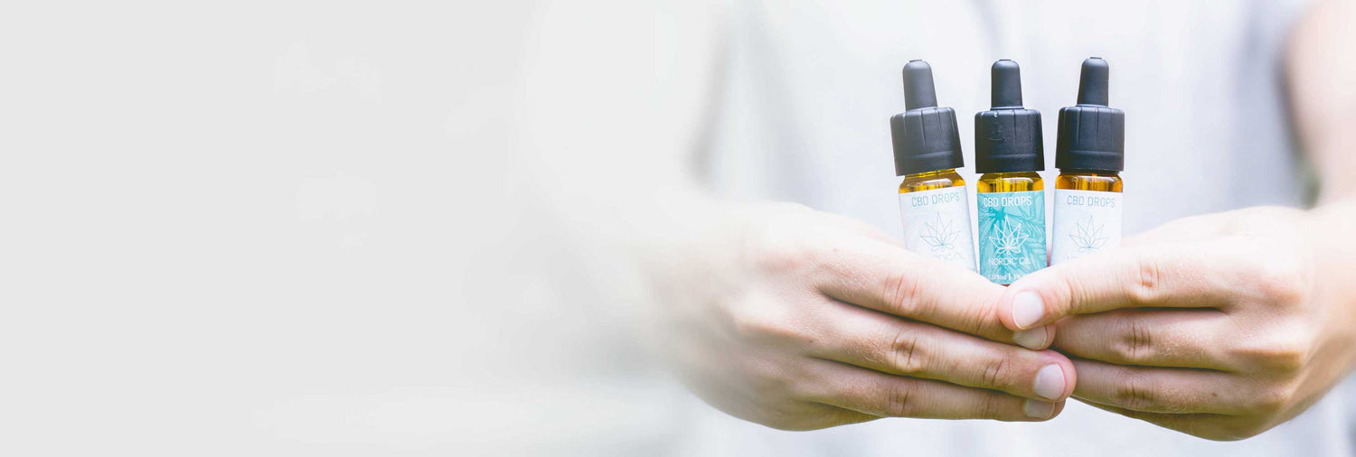 Un uomo porta 3 bottiglie di Olio CBD (15%) e (5%) nelle sue braccia forti