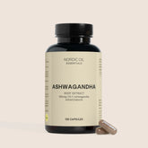 Bottiglia scura di capsule Ashwagandha con etichetta beige Nordic Oil Essentials e due capsule accanto.