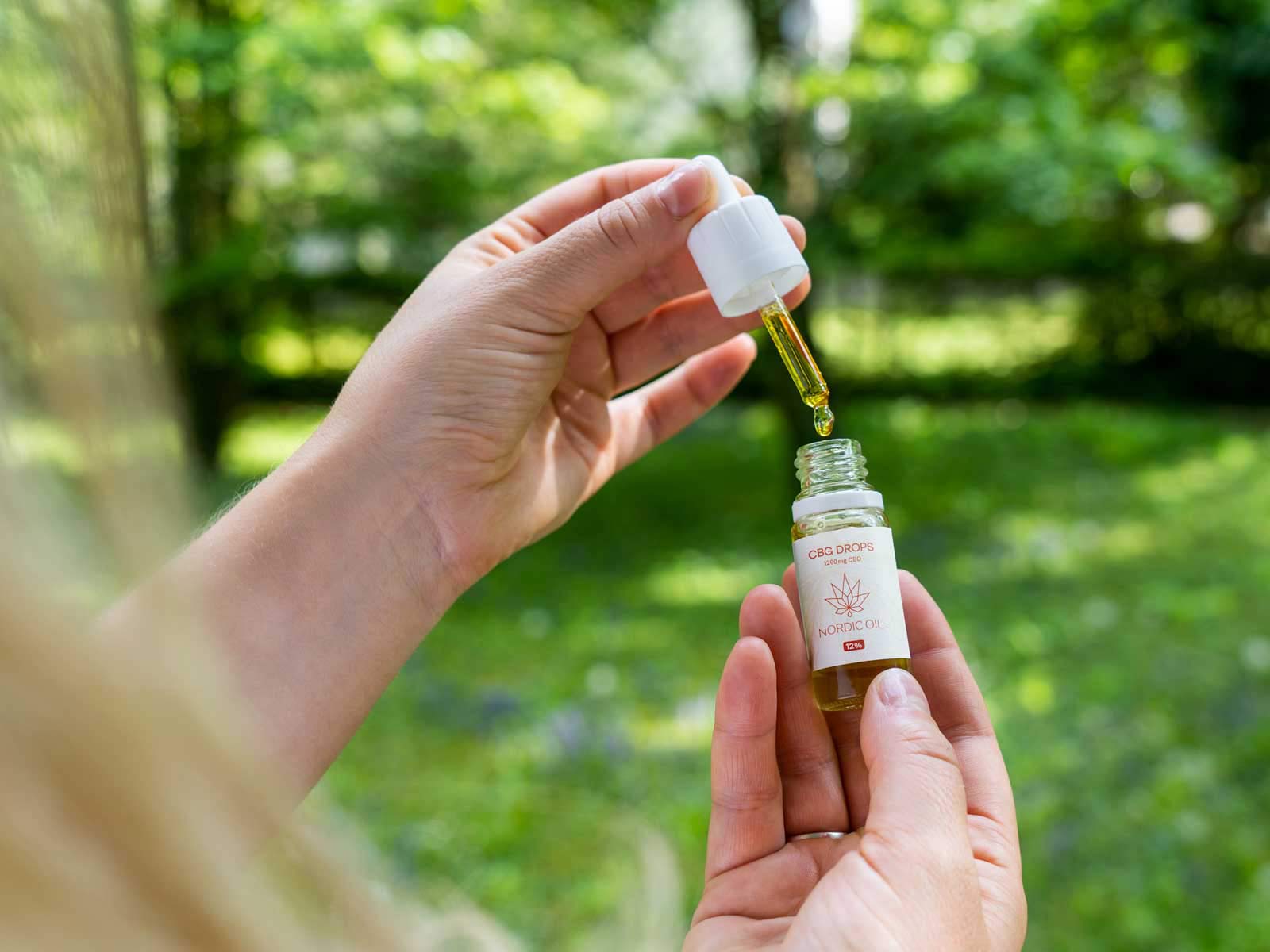Una donna apre una bottiglia di Olio CBG (12%).