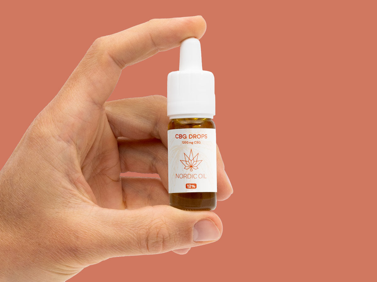 La mano di un uomo regge una bottiglia di Olio CBG (12%).
