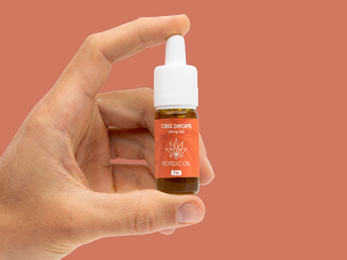 La mano di un uomo regge una bottiglia di Olio CBG (12%).