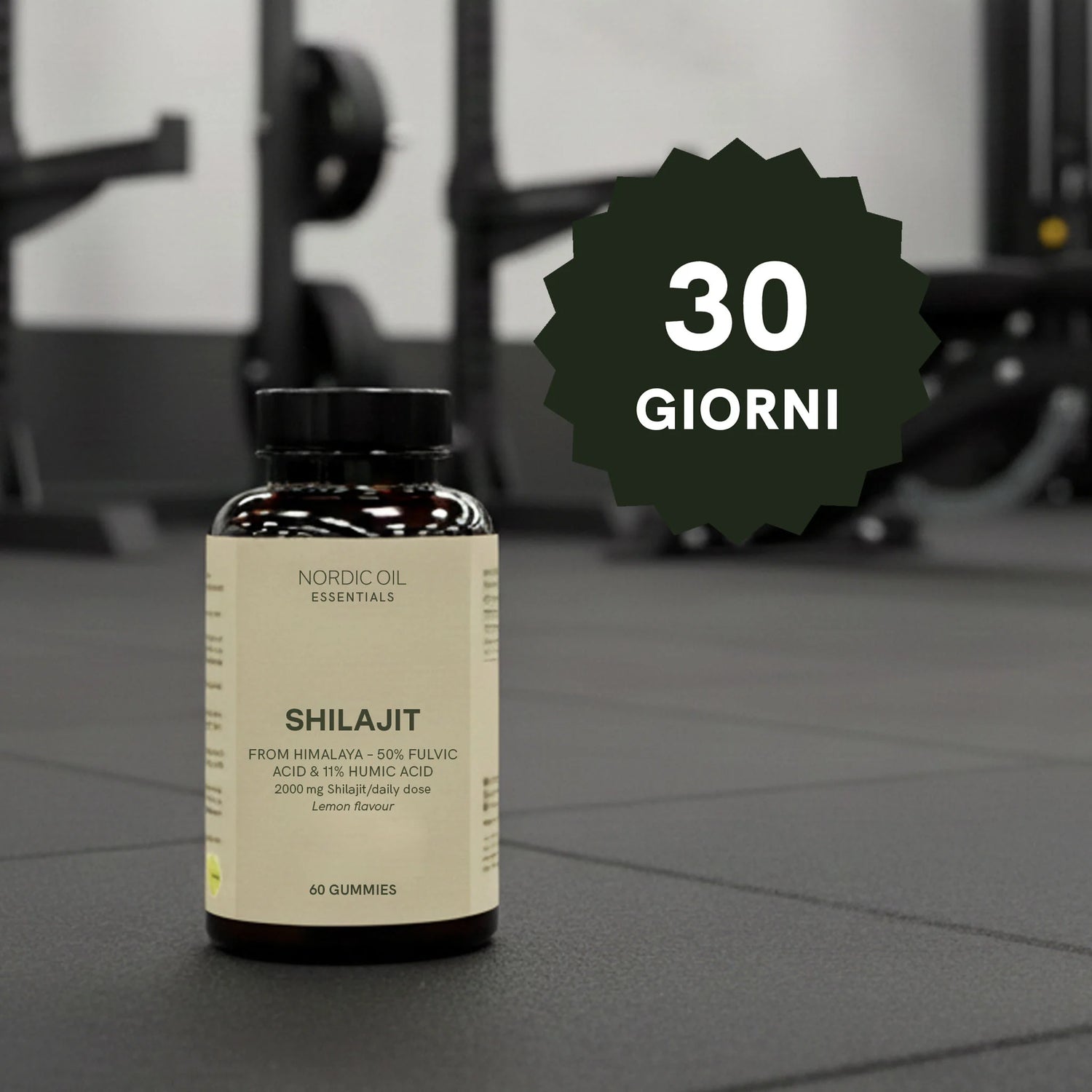 Bottiglia di SHILAJIT Nordic Oil Essentials su pavimento da palestra, con badge verde 30 GIORNI in primo piano.