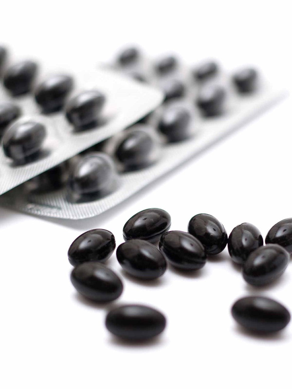 Capsule nere lucide in blister su sfondo bianco