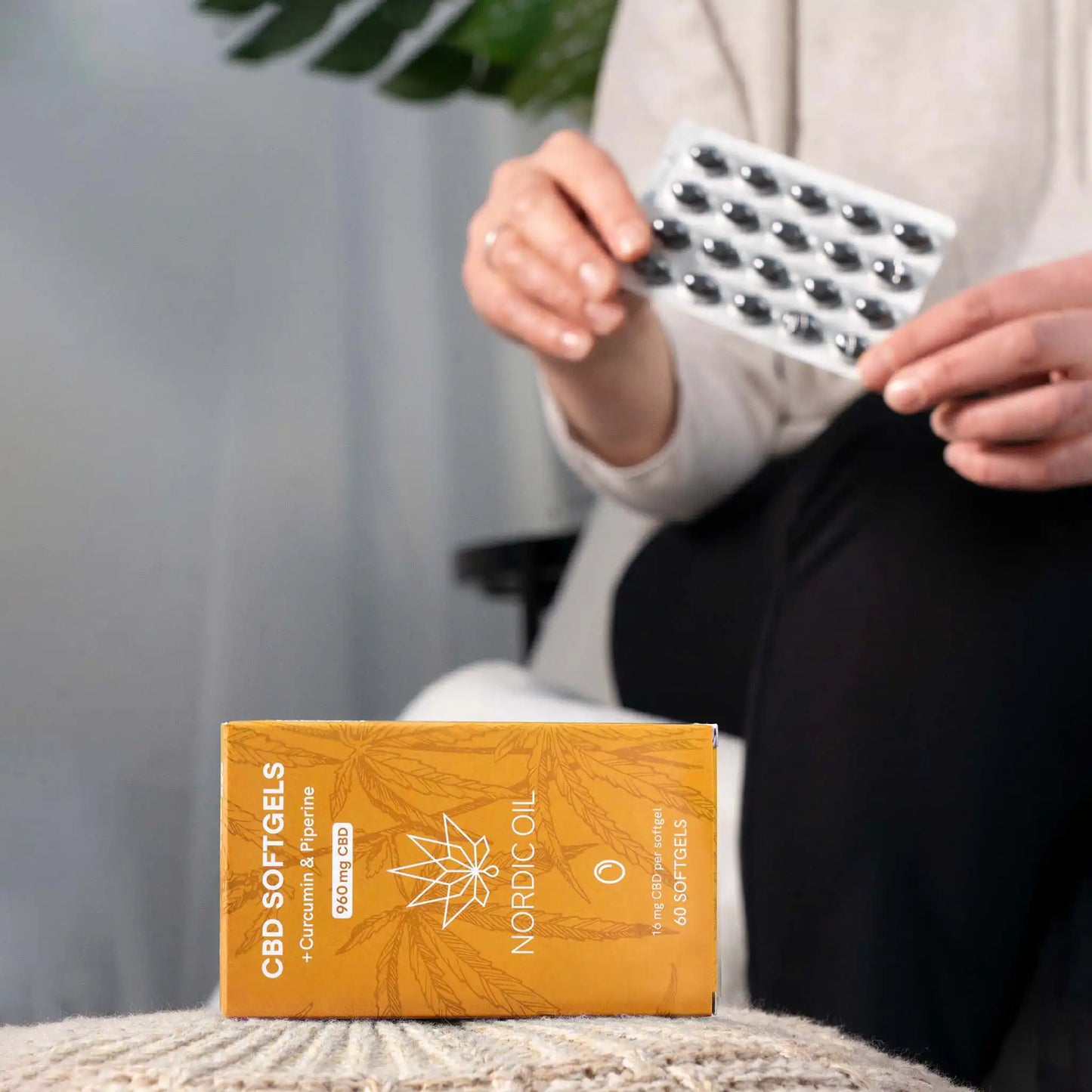 In primo piano, la confezione delle capsule di CBD; sullo sfondo, il cliente tiene le capsule.