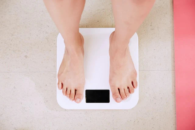 Una persona che controlla il proprio peso corporeo con una bilancia