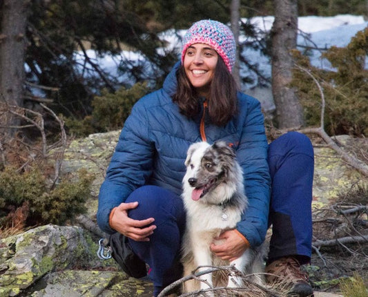 Una donna tiene un cane nella foresta.