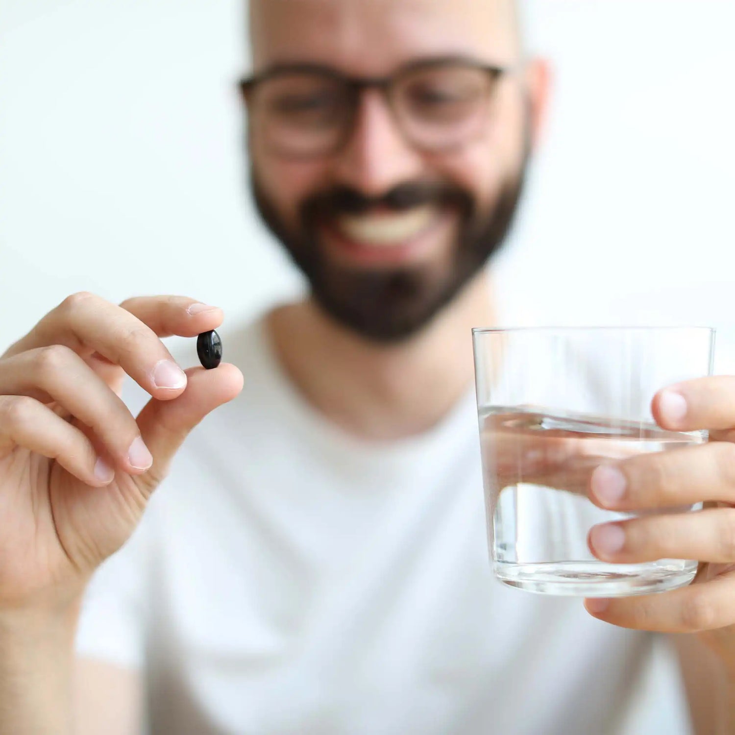 Il paziente tiene in mano un bicchiere d'acqua e una capsula di gelatina morbida.