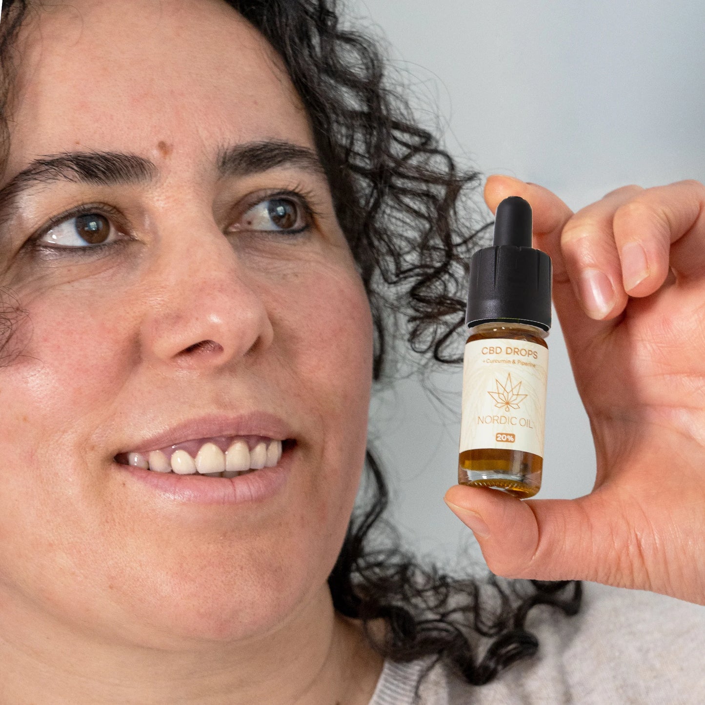 donna che tiene in mano gocce di olio nordico cbd con bottiglia di curcumina