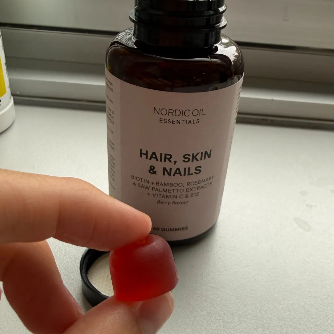 Gommina rossa in primo piano accanto al flacone Nordic Oil Essentials Hair, Skin & Nails