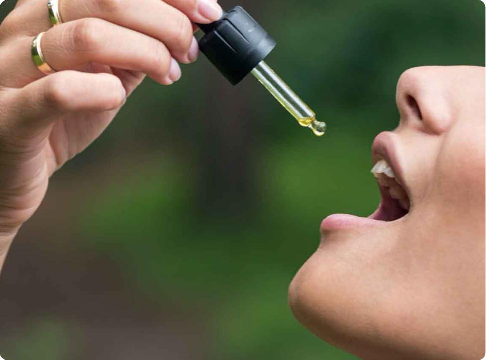 Una donna si versa l'olio di CBD in bocca.