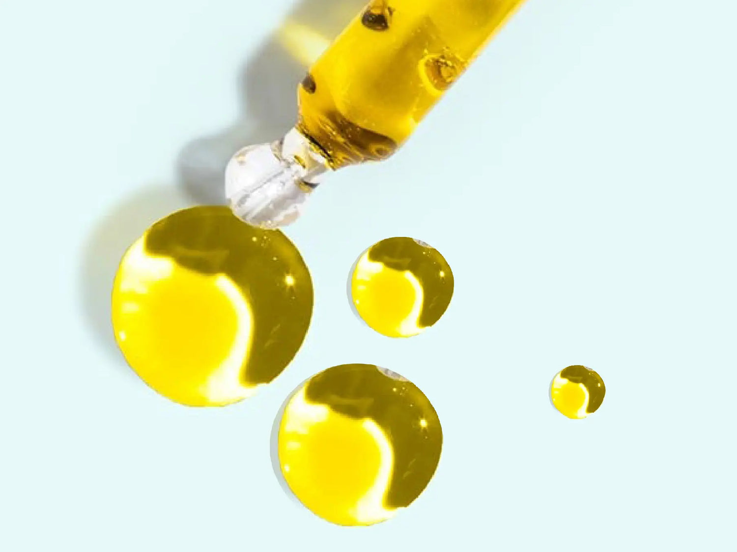 Pipetta e gocce di olio di CBD dal colore dorato
