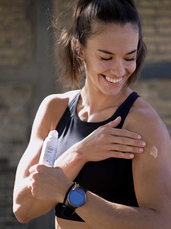 Una donna atletica applica la crema al CBD sulla spalla.