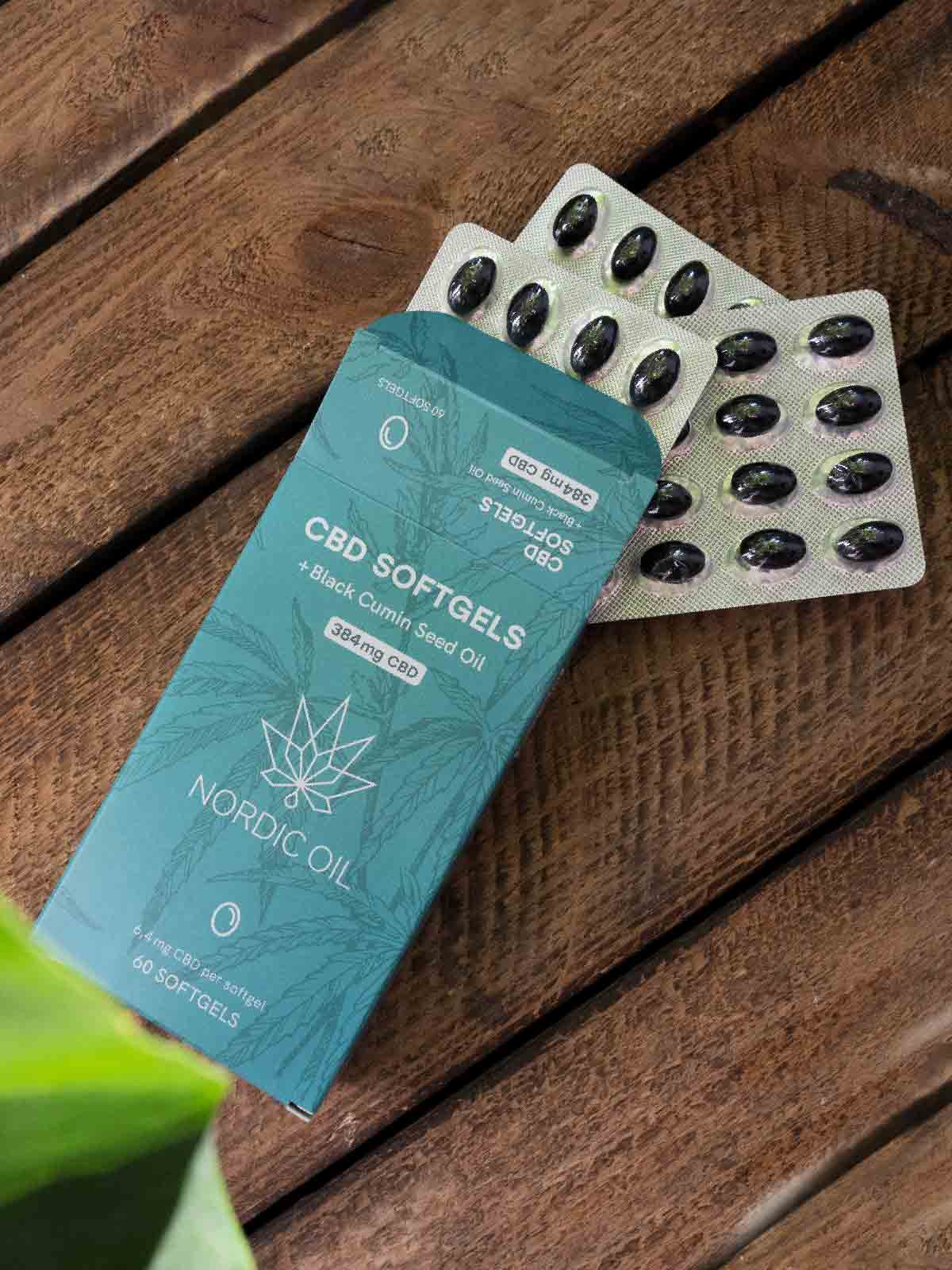 Una confezione di Capsule CBD (384 mg) - Abbonamento giace aperta su un tavolo di legno.